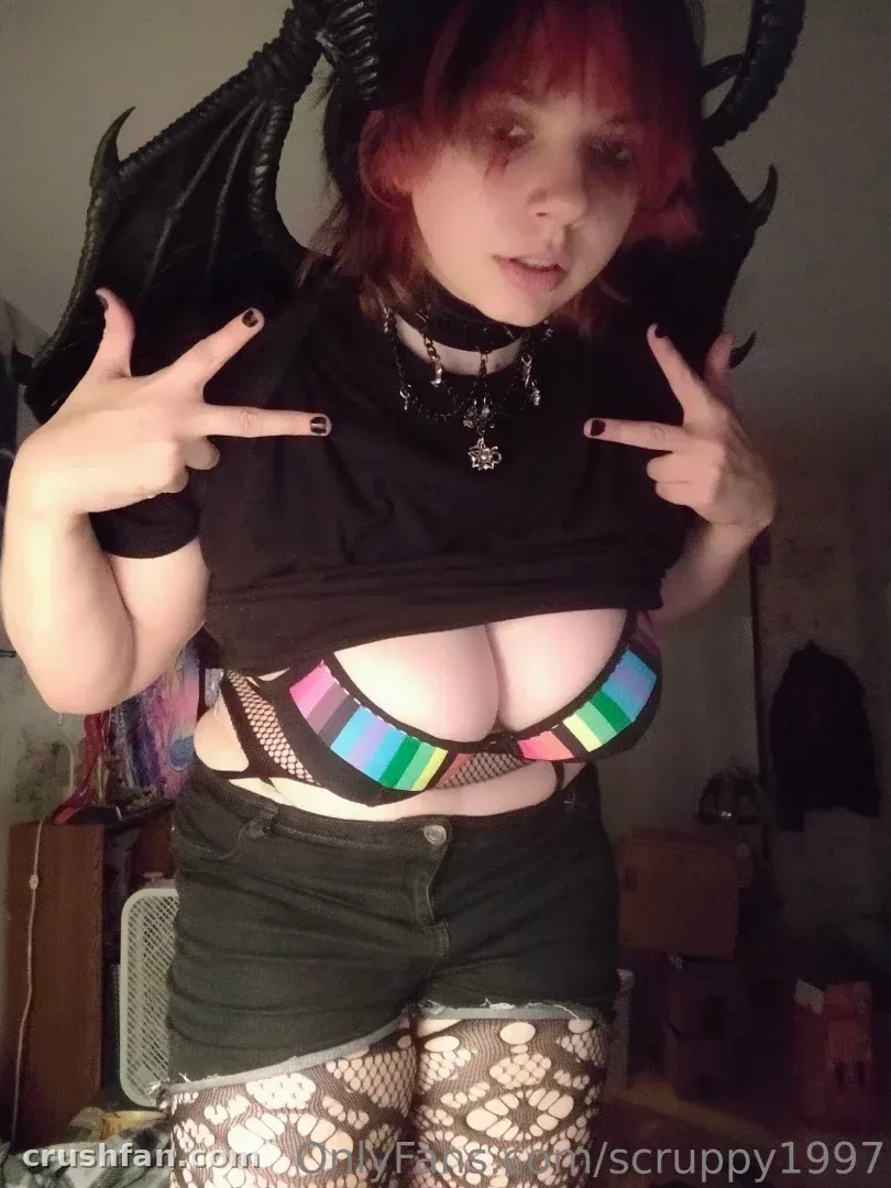 Creator in a black top and shorts with rainbow accents and fishnet tights indoors