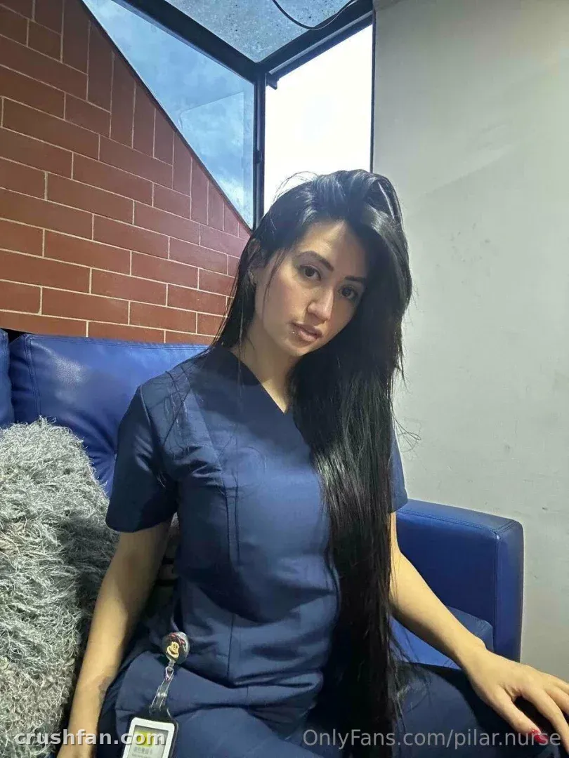 Nurse Pilar in navy scrubs seated on a blue bench indoors