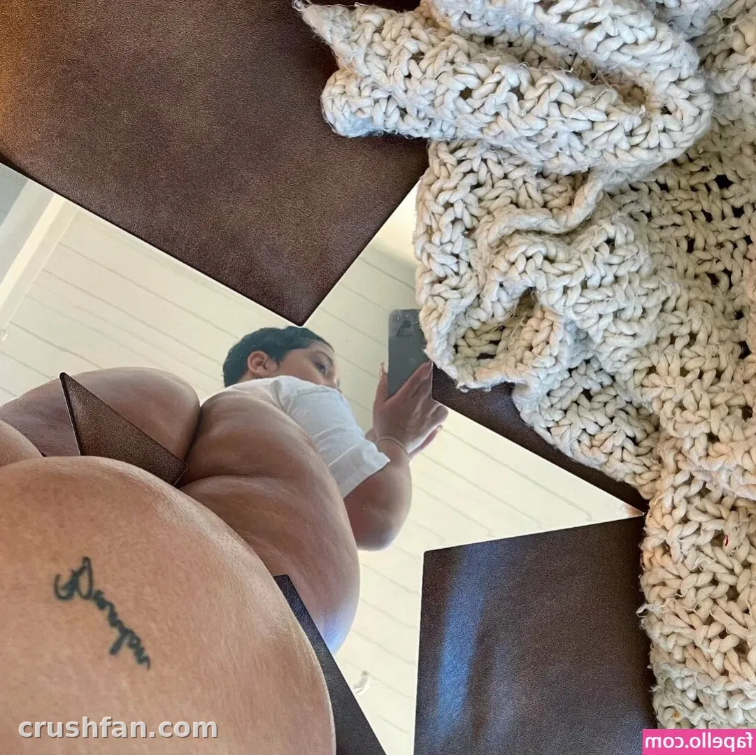 Mirror selfie of AmberThickk in a white top with a cream chunky knit draped nearby.