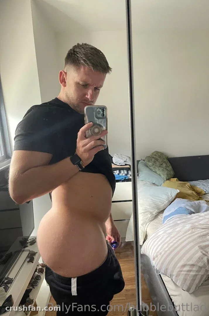 Jay prend un selfie miroir dans une chambre, portant un haut noir et un short sombre.