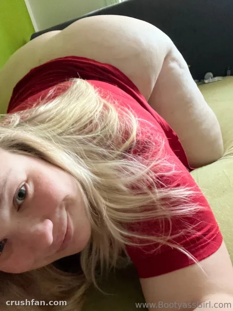 Bootyass Girl с длинными светлыми волосами лежит на зелёной кровати в красном топе