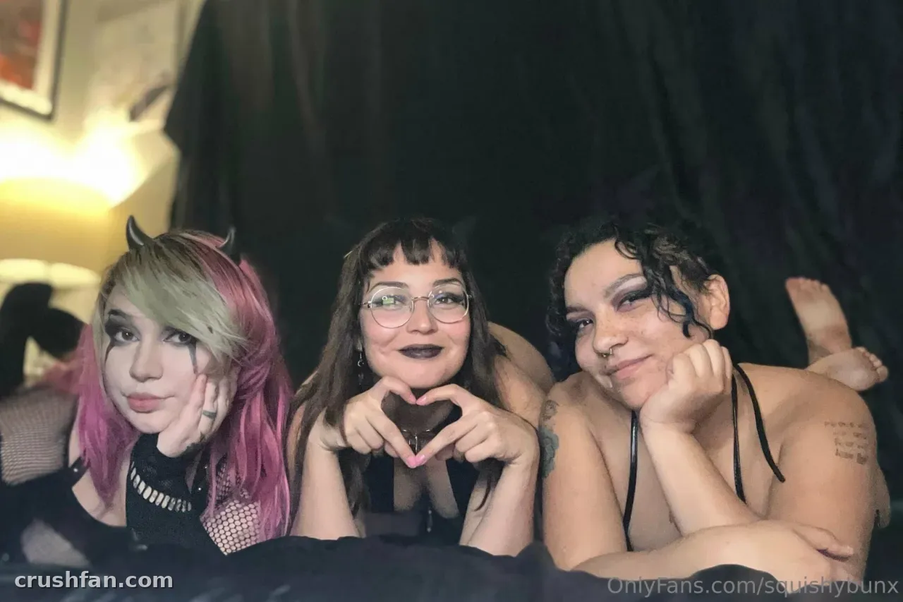 Tres mujeres posan juntas en una habitación oscura de estilo gótico con el resplandor cálido de una lámpara