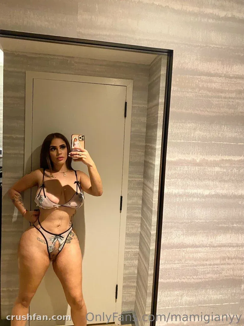 Mami G in floral lingerie taking a mirror selfie in a neutral-toned room