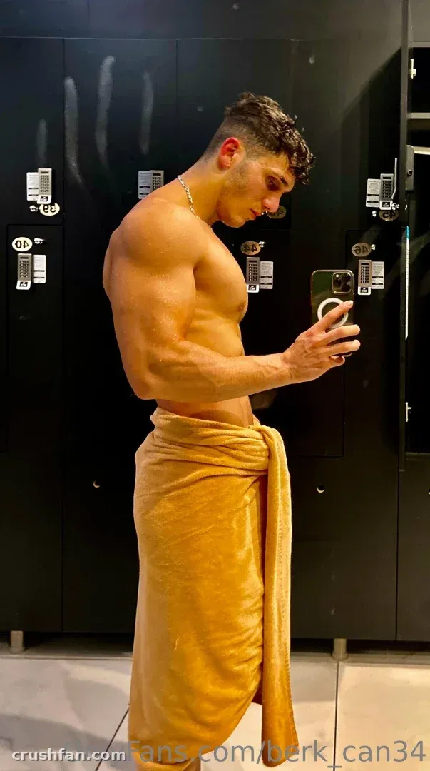Mr. berk macht ein Spiegel-Selfie in einer Umkleidekabine und trägt ein senfgelbes Handtuch.