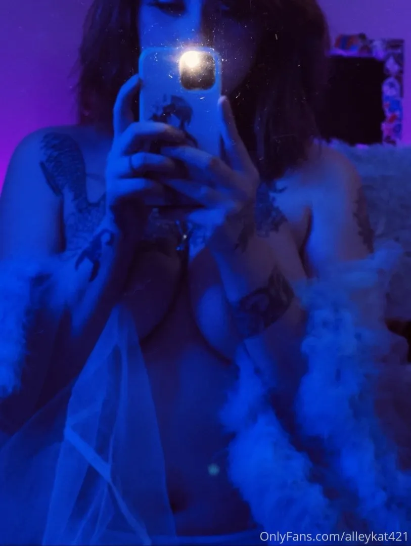 Alley Kat tomándose un selfie de espejo con luz azul y un flash brillante del teléfono