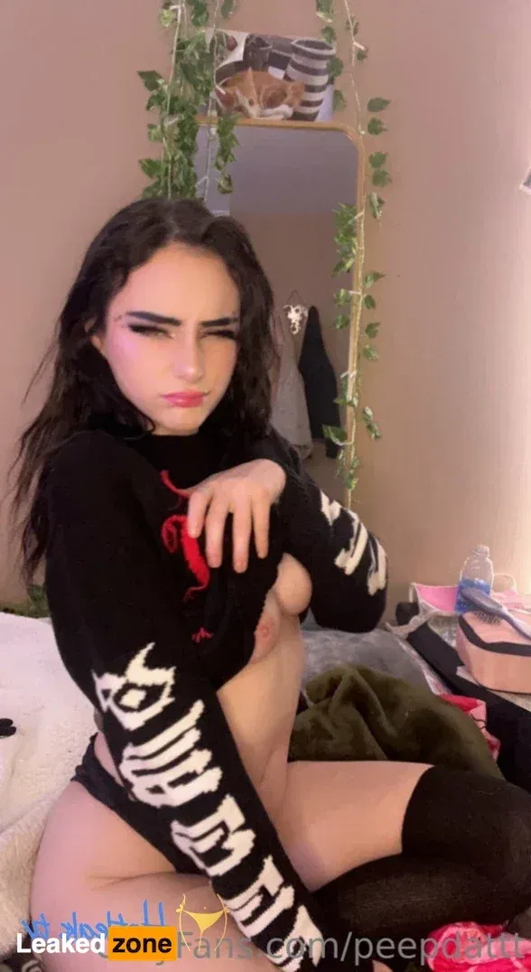 Peep com um suéter de tricô preto e meias até a coxa sentada em ambiente interno perto de um espelho e trepadeiras verdes