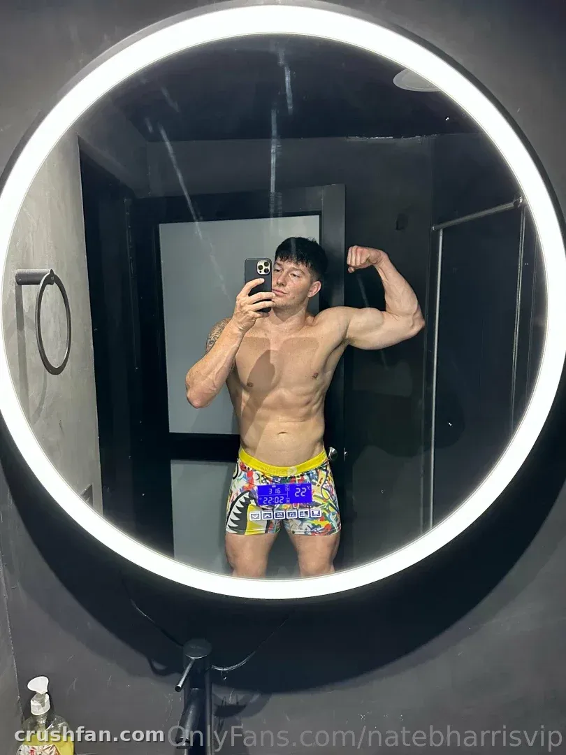 Nate se toma un selfie de espejo en un espejo redondo iluminado con shorts coloridos estampados