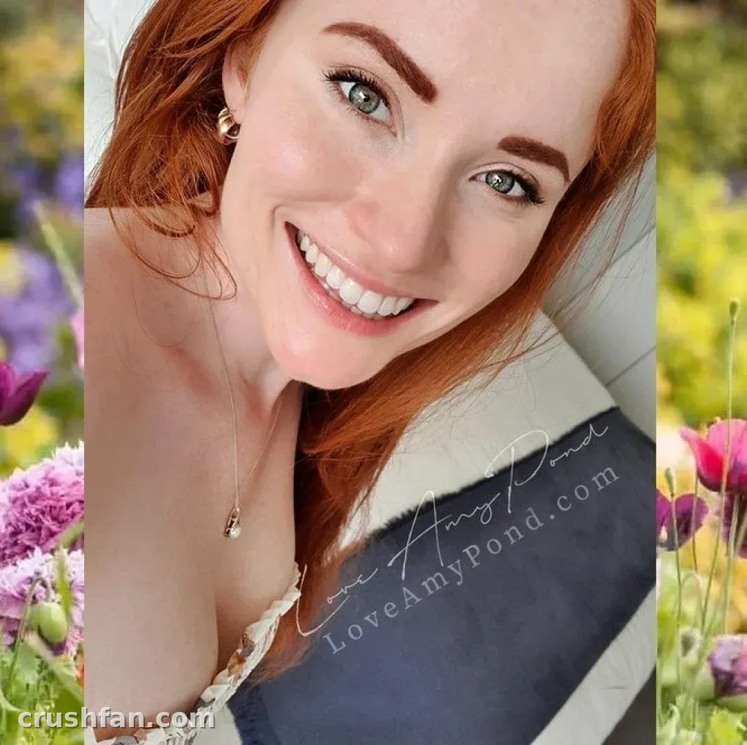 LoveAmyPond smiling in a close-up outdoor portrait with flowers behind her