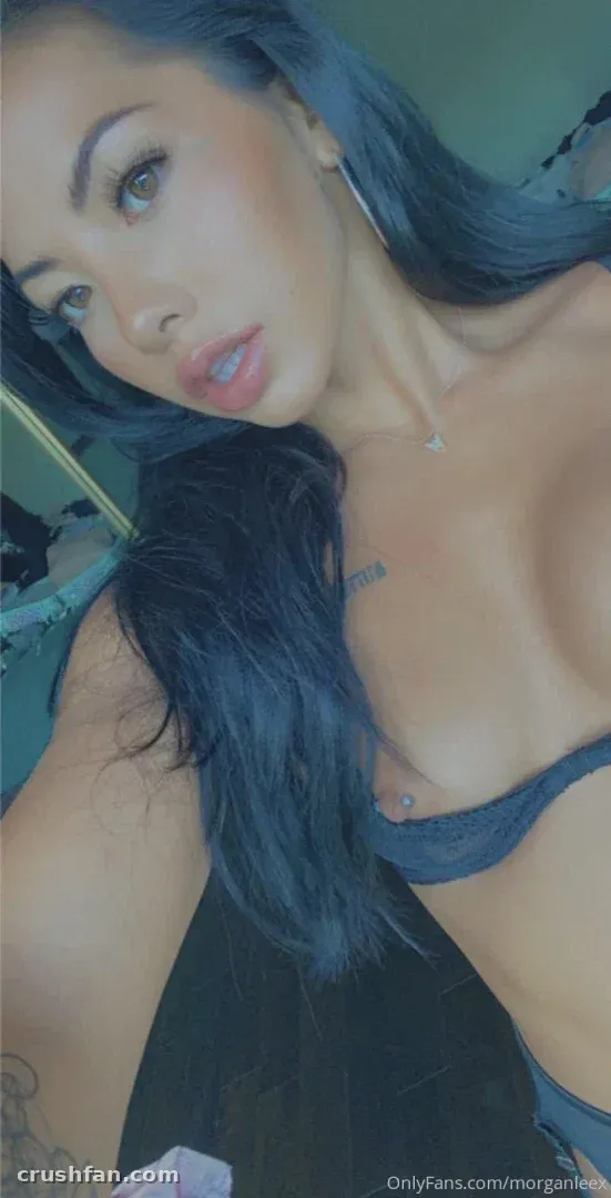 Close-up indoor selfie of a woman with long dark hair wearing a dark blue top