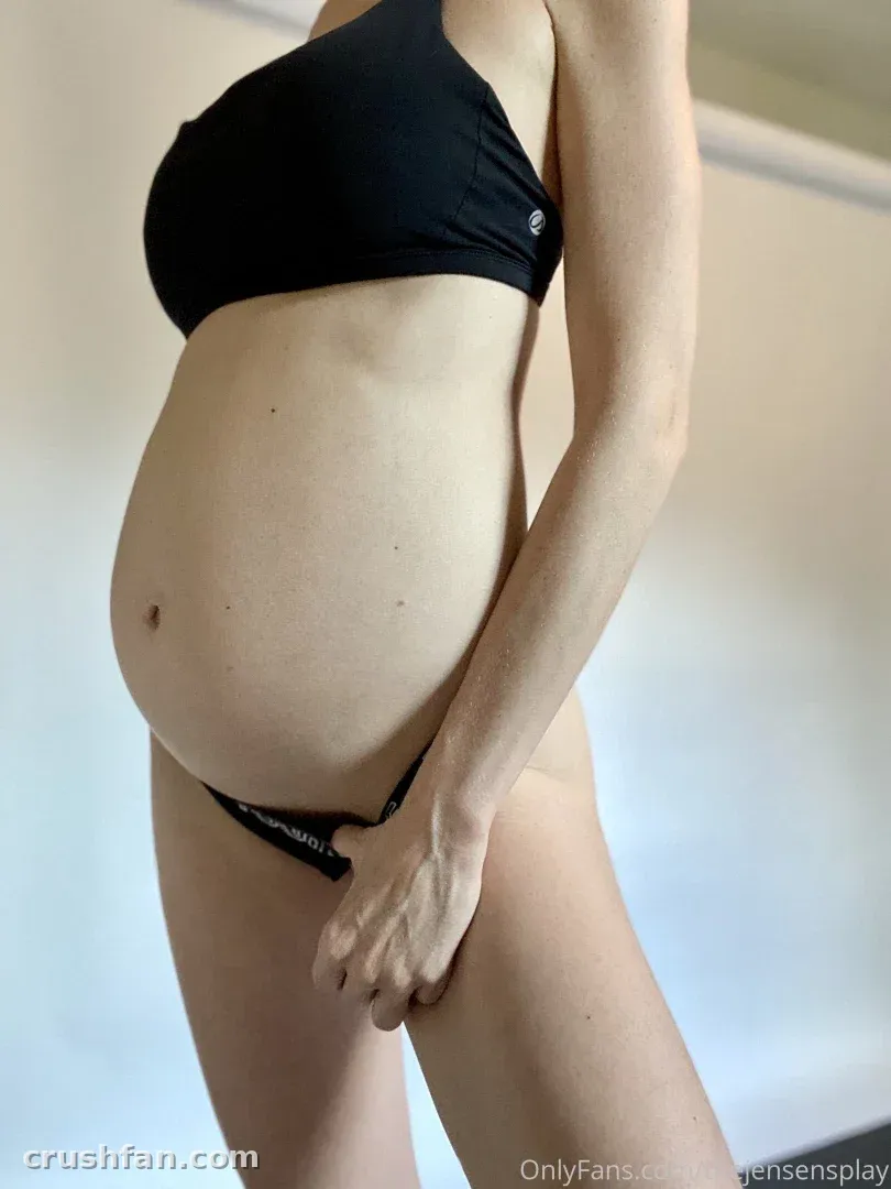 Creator in black two-piece swimwear standing in side profile against a light wall.