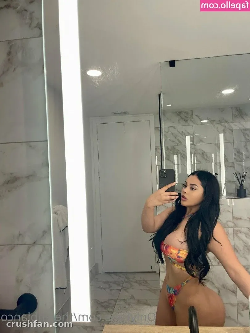 Jen in a colourful two-piece set taking a mirror selfie in a marble-tiled bathroom.