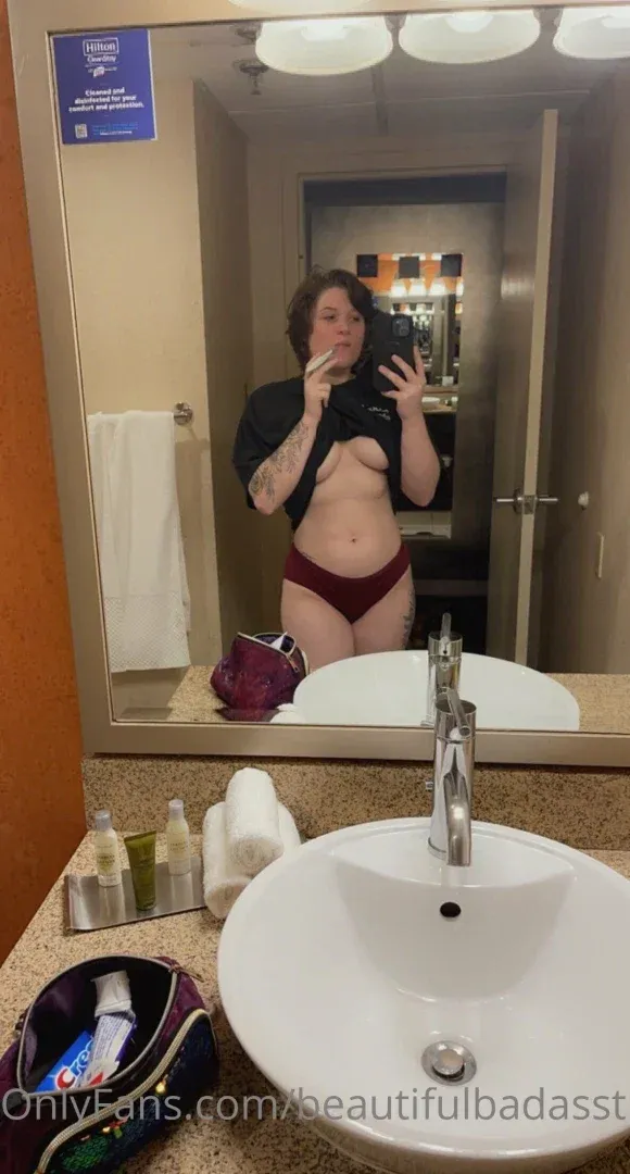 Jess taking a mirror selfie in a hotel bathroom, wearing a dark top and red underwear.