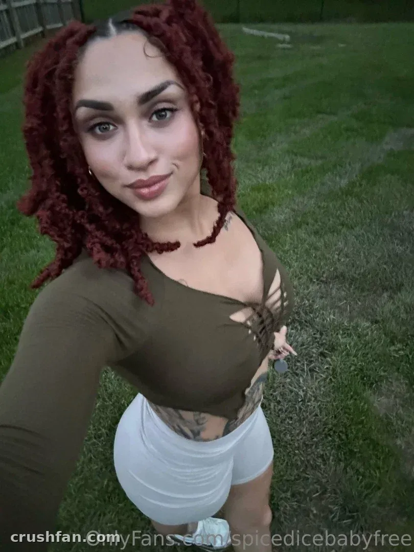Creator in an olive top and white shorts taking an outdoor selfie on grass