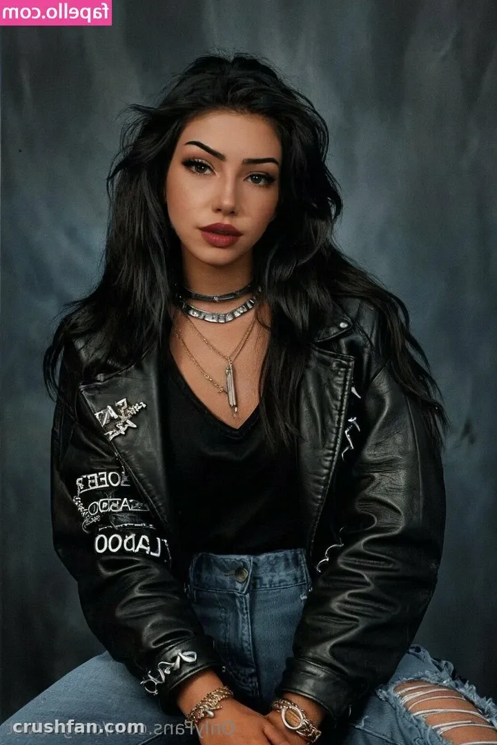 Velvet in einer schwarzen Lederjacke und blauen Jeans vor grauem Studiohintergrund