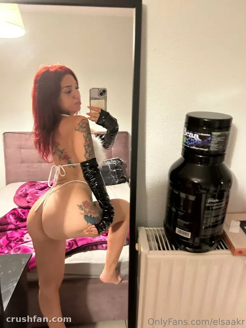 Elisabeth takes a mirror selfie in a white bikini and long black gloves.