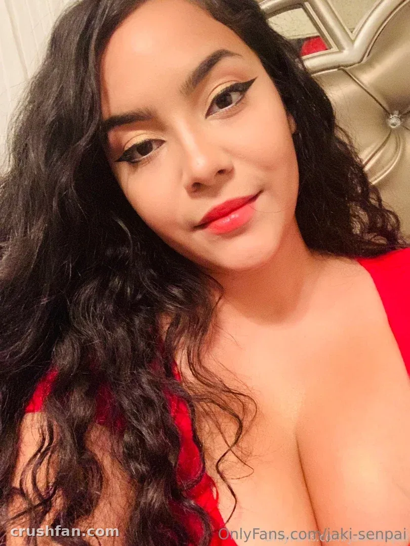 Selfie de cerca de una mujer con largo cabello oscuro ondulado, labios rojos y un top rojo