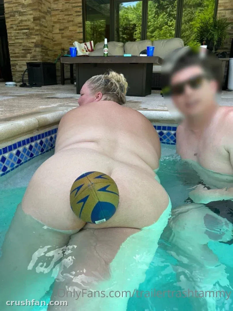 Chelcie Lynn in a pool holding a volleyball behind her back with a blurred person nearby