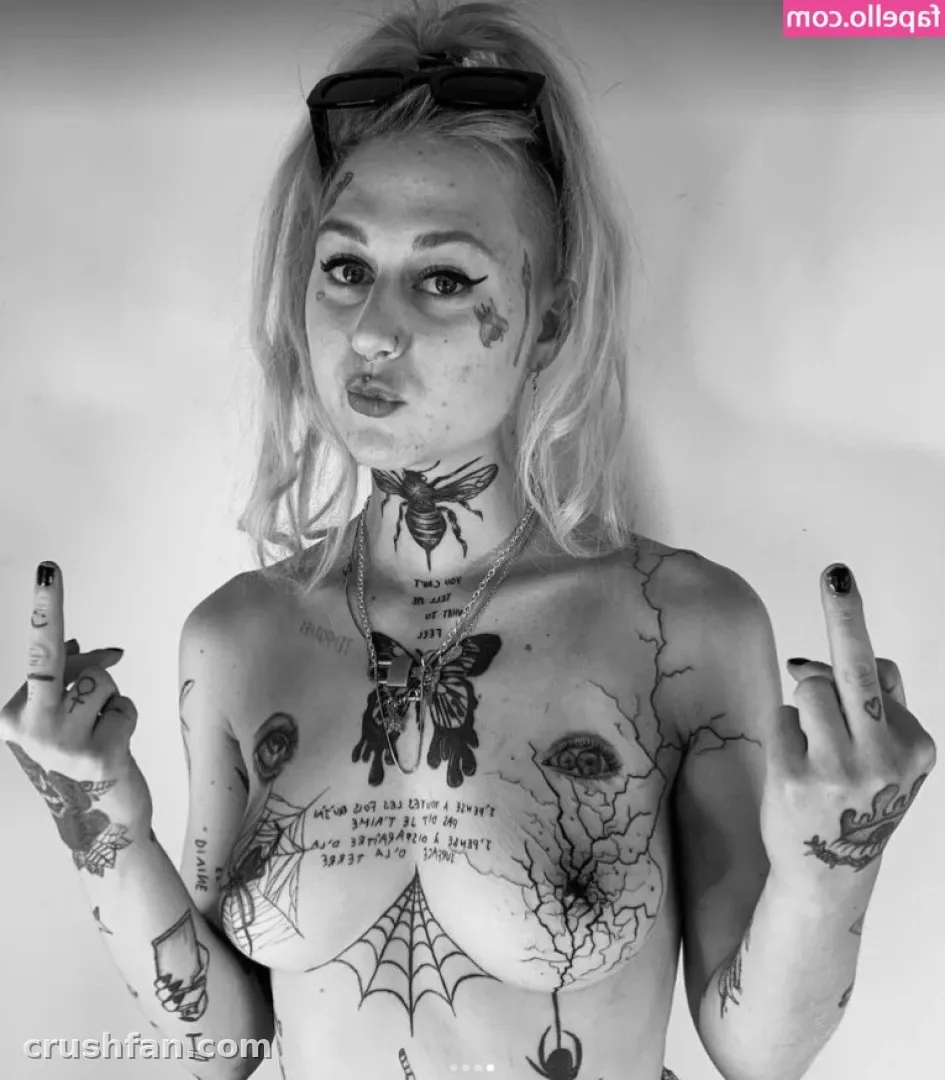 Black and white portrait of EJ with sunglasses on her head, tattoos and raised hands
