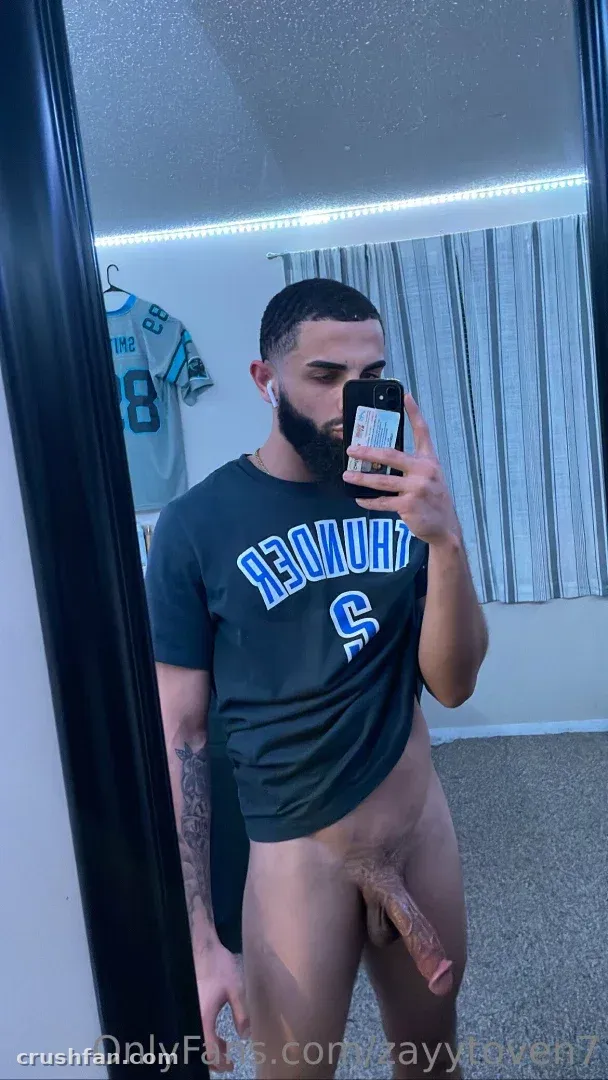 Zayytoven7 takes a mirror selfie in a dark sports jersey indoors.