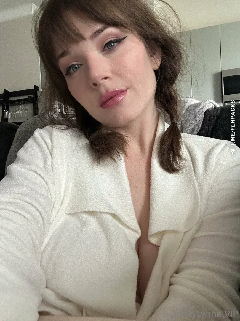 Emily Lynne in a cream blouse indoors with pigtails and soft lighting