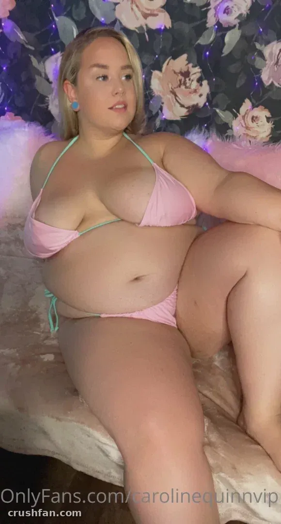 Caroline Quinn in einem rosa Bikini vor einer floralen Kulisse
