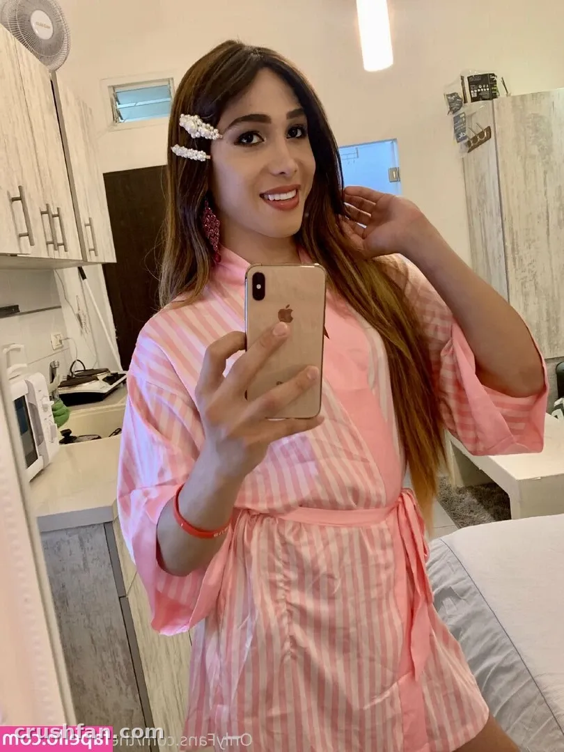 Creator in a pink striped robe taking a mirror selfie in a kitchen