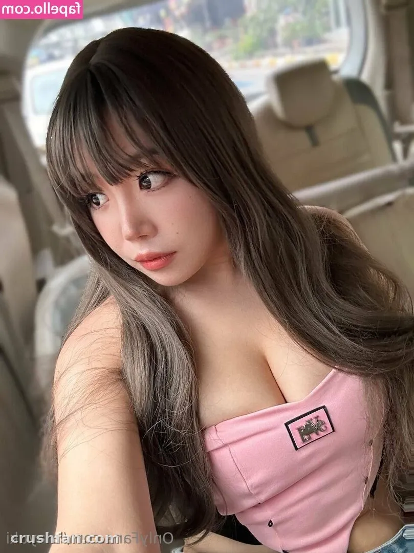 Yuki com uma blusa rosa olhando para o lado dentro de um carro