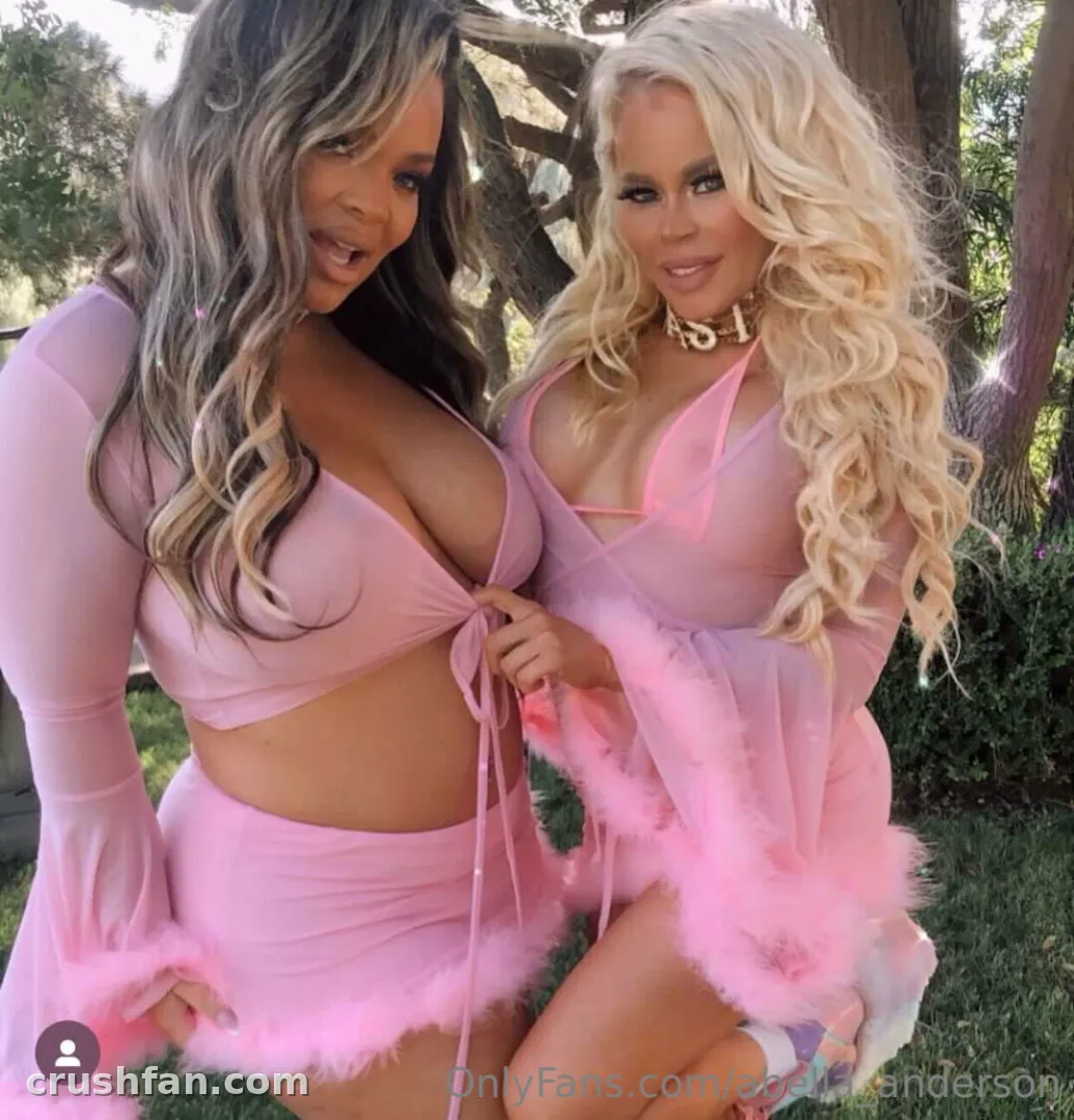 Creator com um look rosa com detalhe de penas posando ao ar livre entre árvores sob luz suave do dia