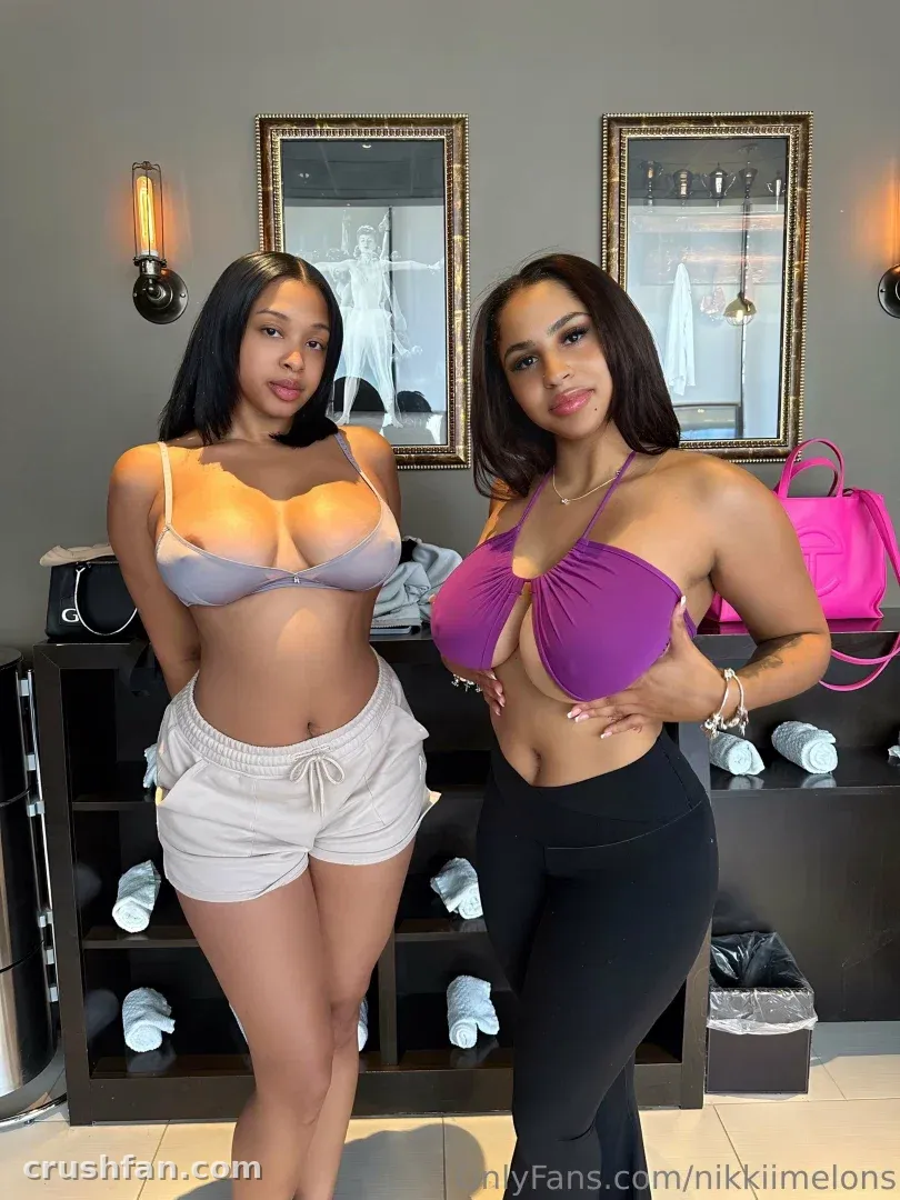 Two women posing indoors, one in a grey bikini top and shorts, the other in a purple top and black leggings.