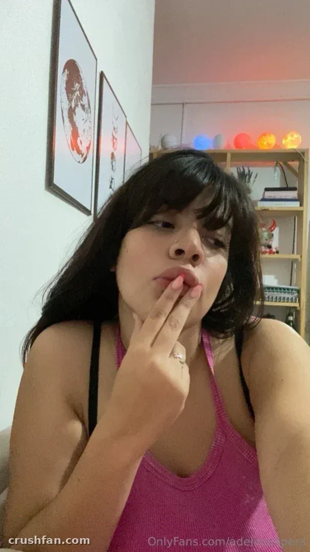 Adelina Lopera con un top rosa en interiores con arte enmarcado detrás de ella