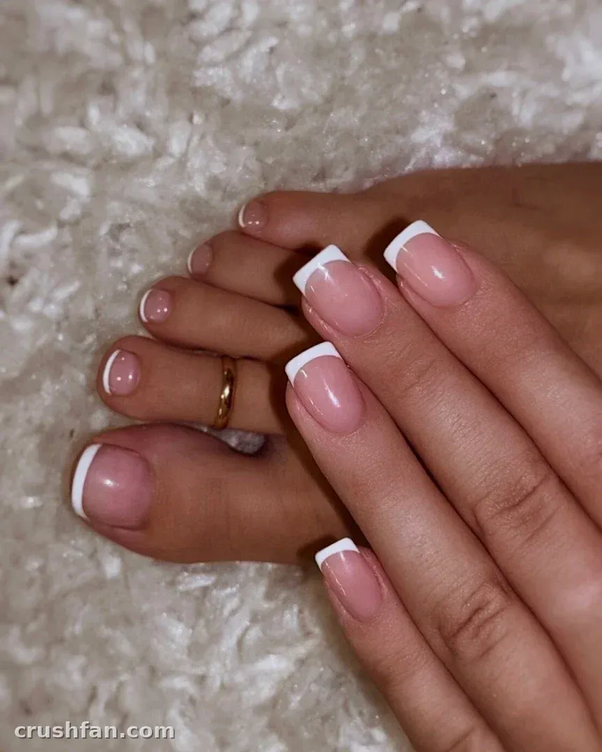 Close-up of Bec's hands and feet with a French manicure on a fluffy surface