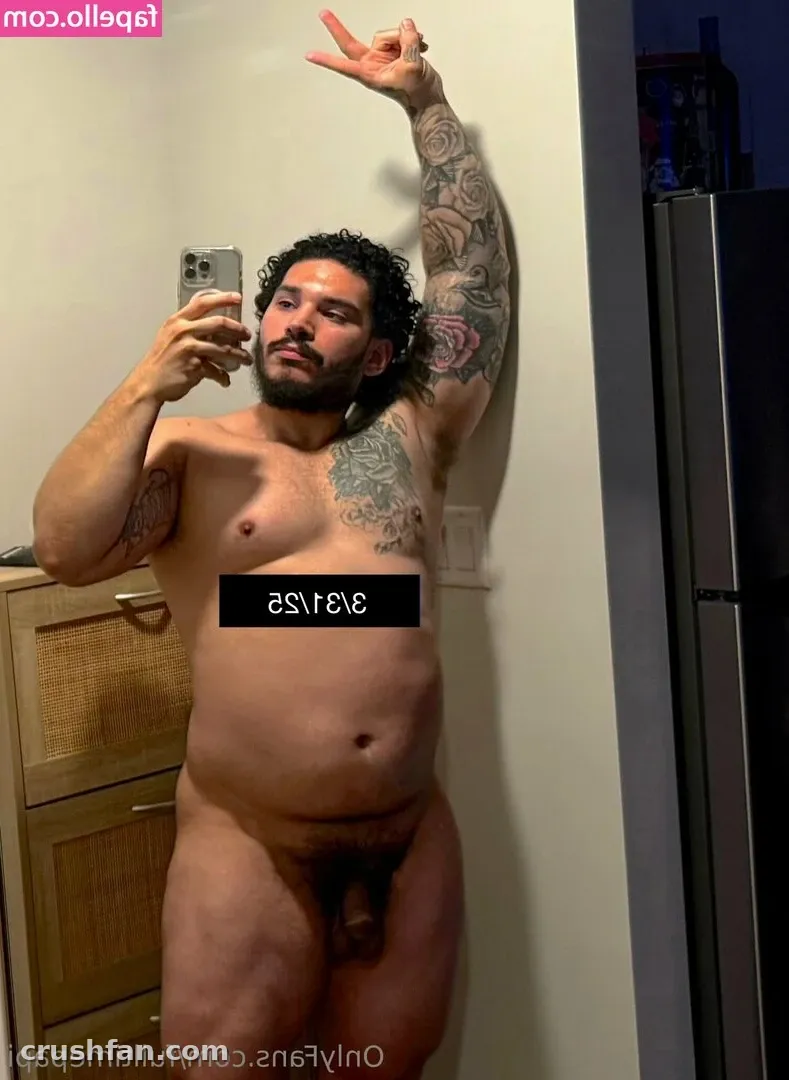 Diego Grant taking a mirror selfie with one arm raised, showing chest and arm tattoos.