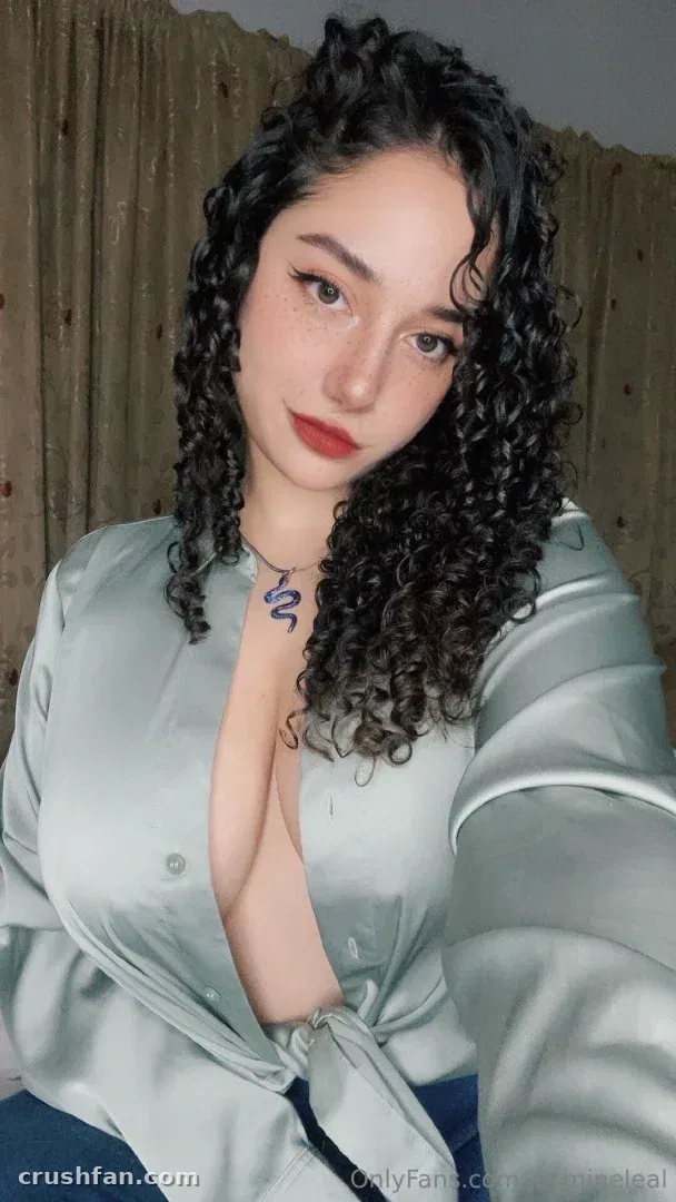 Jasmine Leal in einer Satinbluse in Salbeifarbe vor einem beigen Vorhang