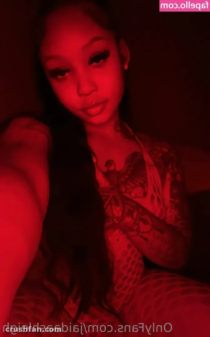 Red-lit close-up selfie of tasteofJaida with dark hair and a tattooed arm.