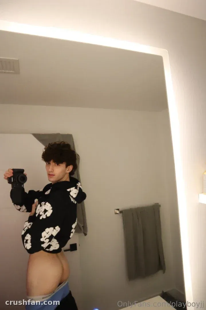 Jayden in a black floral hoodie taking a mirror selfie in a bathroom
