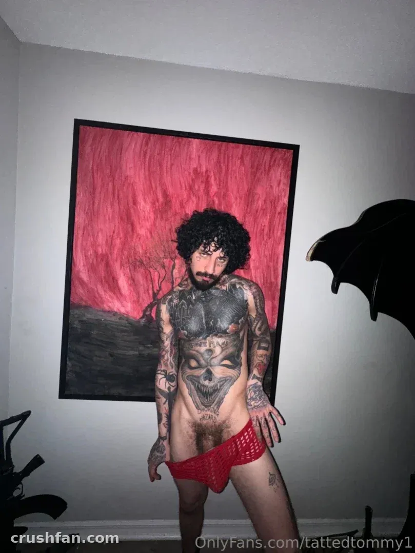 Tommy en slip rouge debout devant une grande peinture rouge et noire dans une pièce lumineuse