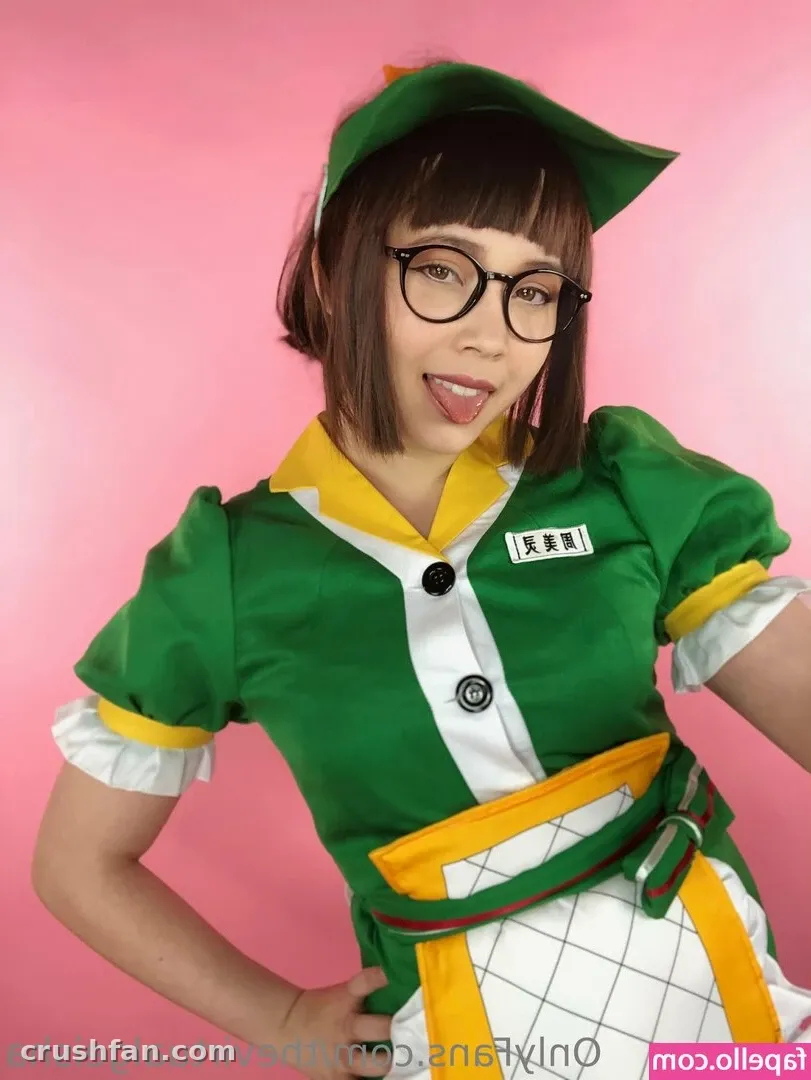 Creadora con un atuendo cosplay verde y gafas sonriendo frente a un fondo rosa