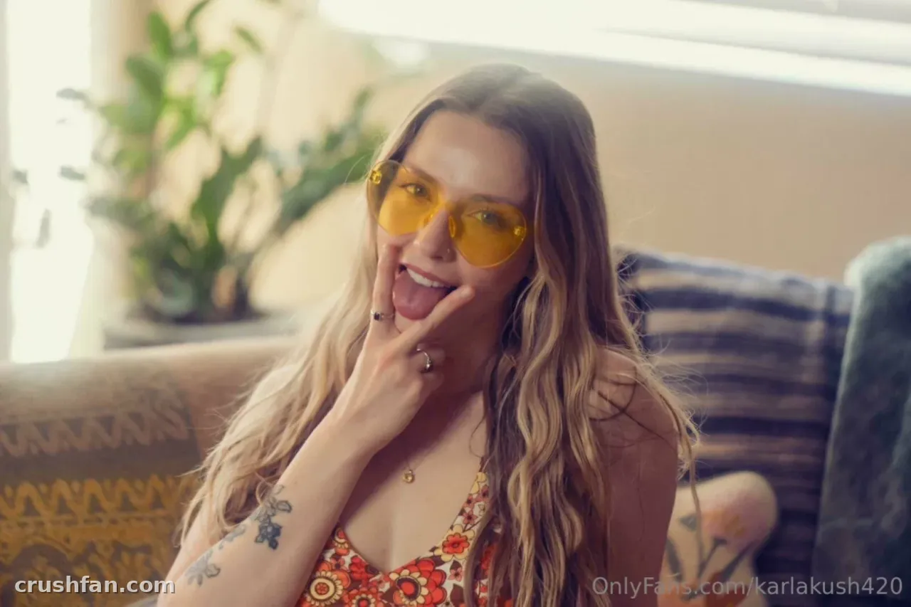 Woman in yellow-tinted glasses and a floral top smiling indoors on a patterned sofa