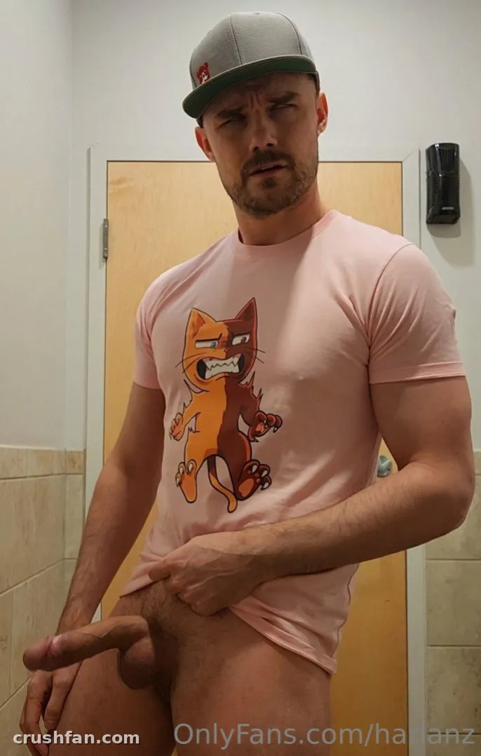 Harlan con una camiseta rosa de gato de dibujos animados y gorra gris de pie en el interior