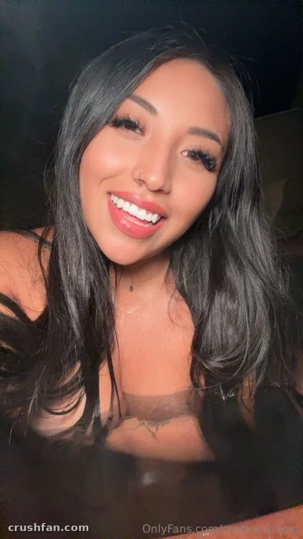 Cristina smiling in a close-up selfie with long dark hair and warm lighting.