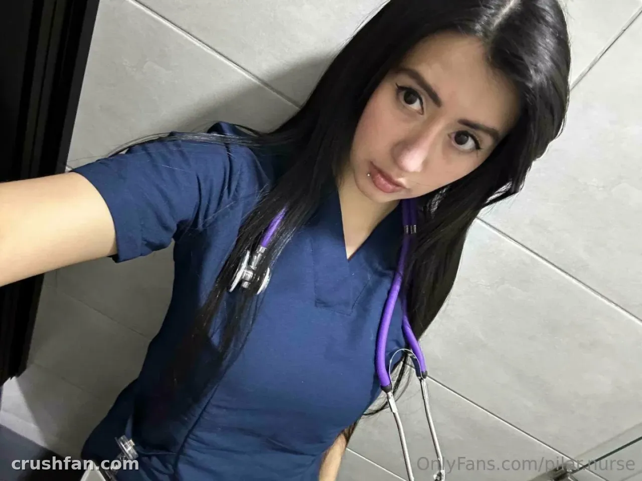 Nurse Pilar in blue scrubs with a purple stethoscope around her neck taking a selfie.