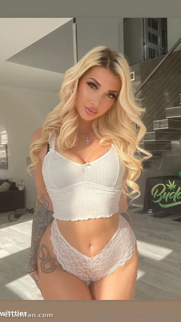 Creator com um top cropped branco canelado e calcinha de renda em ambiente interno, longo cabelo loiro ondulado, iluminação suave.