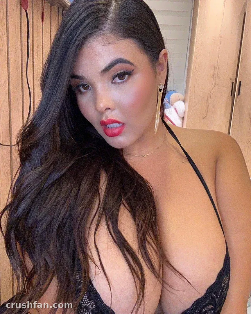 Close selfie of Daniela Arcila with long dark wavy hair and red lipstick indoors