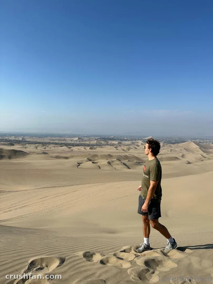 Leo standing on a sand dune in a desert landscape under a clear blue sky.