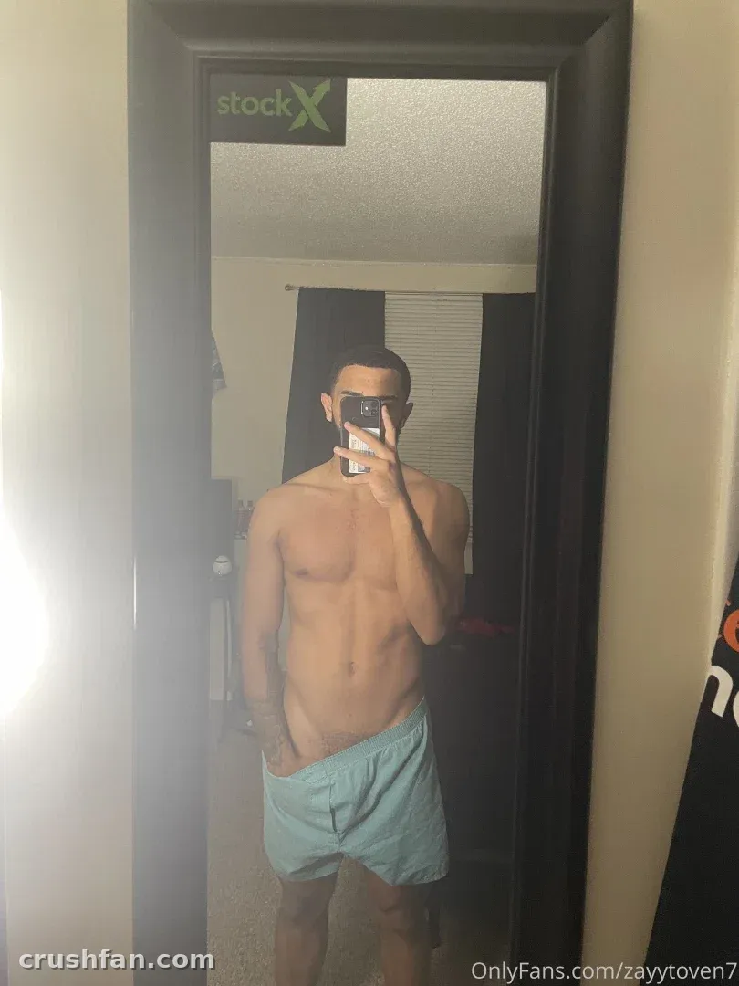 Shirtless mirror selfie of a creator in light blue shorts indoors