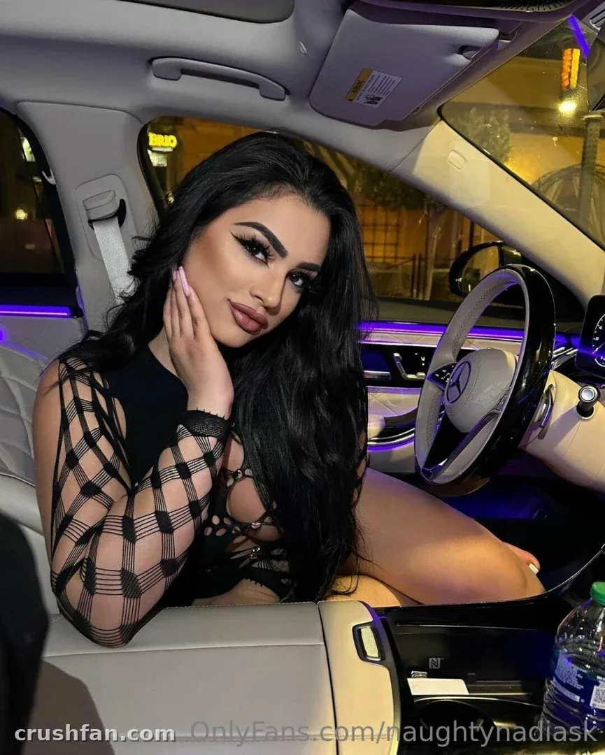 Nadia dans une voiture la nuit, portant un haut sombre à manches transparentes à carreaux sous un éclairage violet