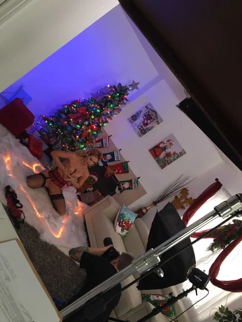 Cherie DeVille em um estúdio festivo com uma árvore de Natal e equipe de câmera.