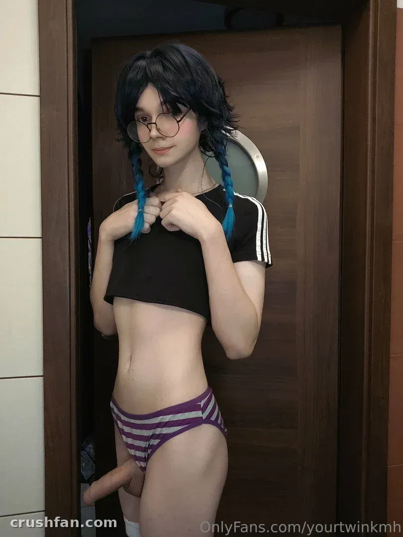 Creator with blue-tipped braids and round glasses posing in a doorway in a black crop top.