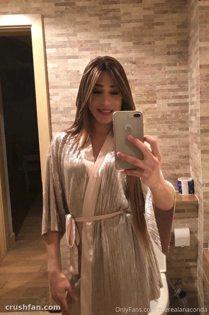Creator in a shimmering robe taking a mirror selfie in a tiled bathroom