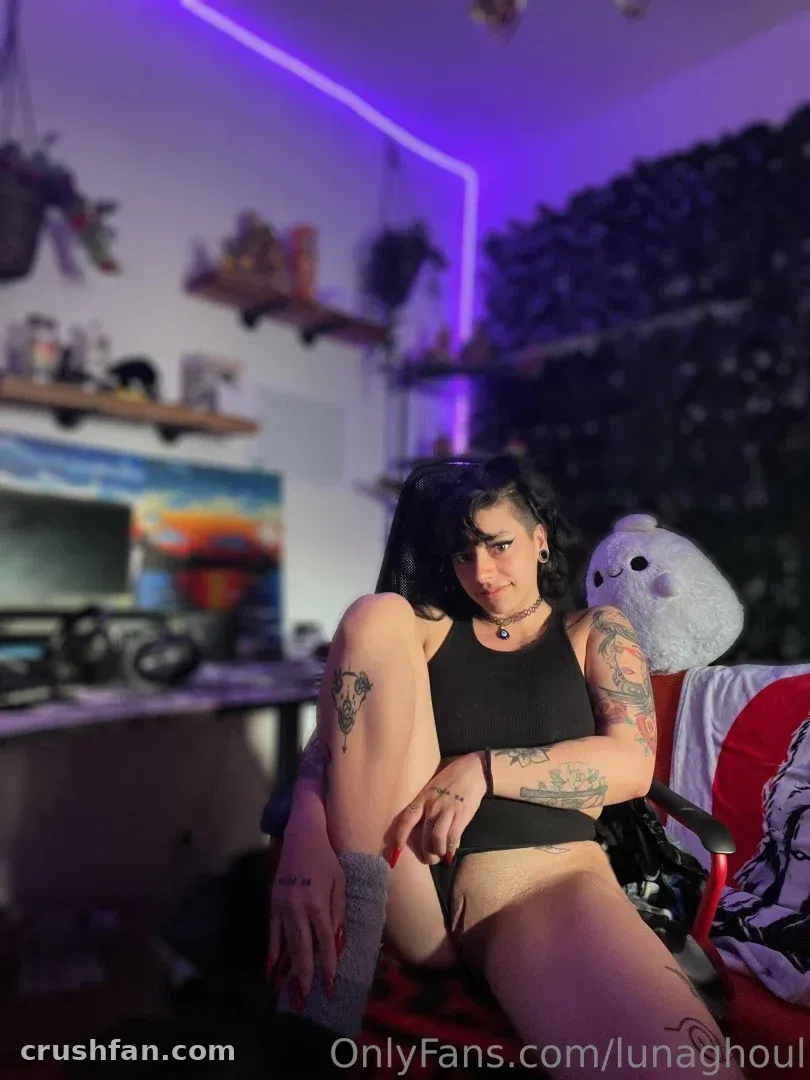 Luna sitzt in einem Gaming-Stuhl in einem violett beleuchteten Raum mit Regalen und einem Plüschtier
